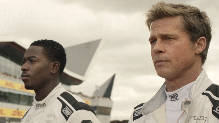 Two race car drivers standing side by side and looking off screen.