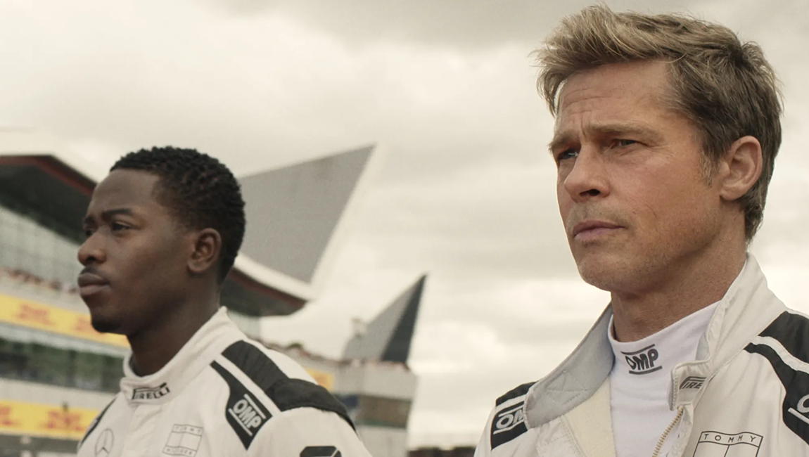 Two race car drivers standing side by side and looking off screen.