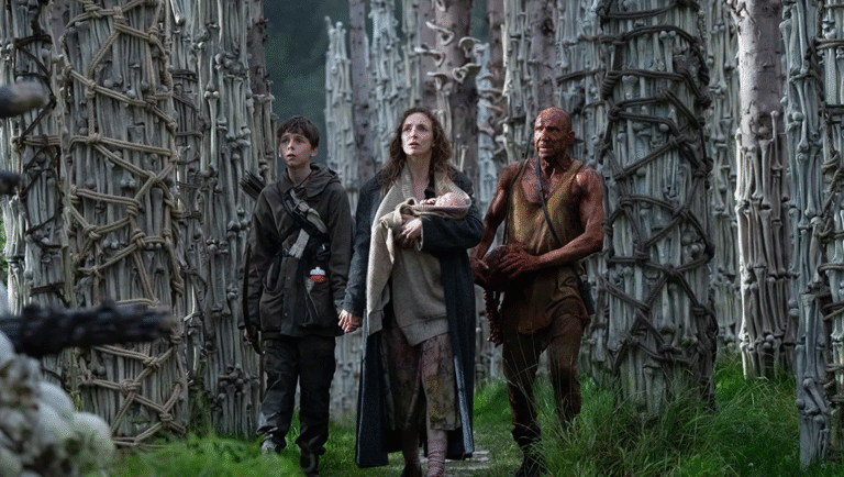 A young boy, a woman, and a shirtless, dirt-covered man stand amidst grass, vines, and trees.