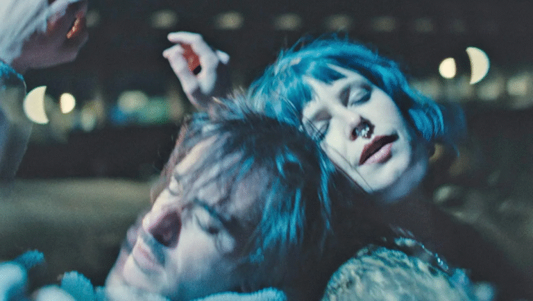 How to Shoot a Ghost film still. Woman with blue hair and nose ring leans on a man.