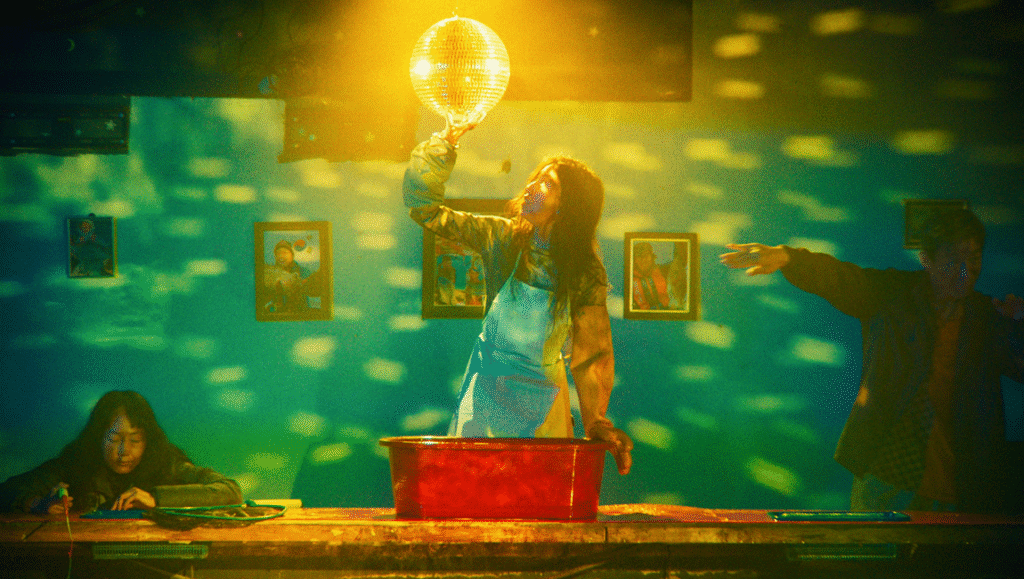 Indoor scene with people, disco ball, and a red tub. Light reflects off wall. Party atmosphere.