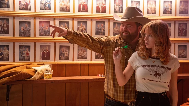 Americana movie scene: Sydney Sweeney and Eric Dane in a bar with dartboard. Lionsgate film.