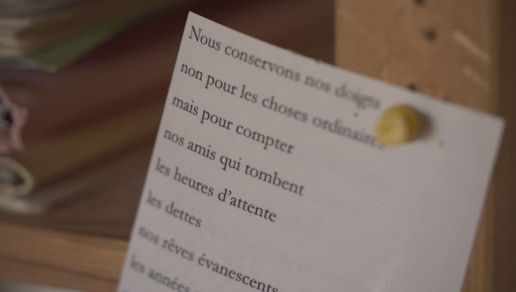 French text on paper, Nous conservons nos dons, pinned to a board. Workshop film still.