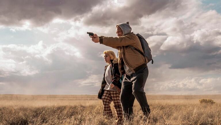 Sheridans Shotgun movie scene. Man aims gun, child watches. Lionsgate film, action, drama, crime. Outdoor landscape.