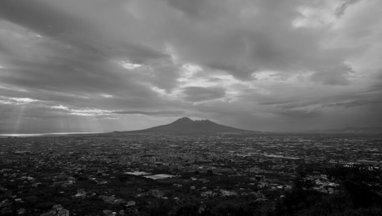 Black and white view of Mount Vesuvius and Naples under a cloudy sky.