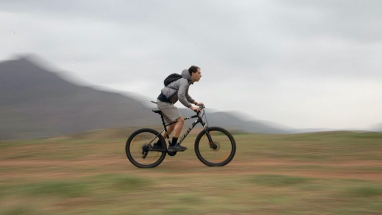 Actor Sajjad Hamidian rides a bike in Inside Amir, Venice Film Festival 2025. Mountain landscape background.