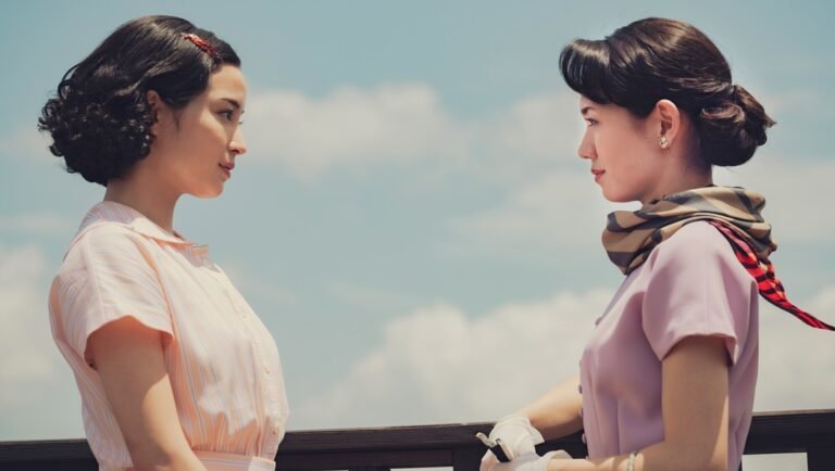 Two women face each other in vintage attire. Retro fashion, stylish scarf, classic hairstyles, and clear blue sky.