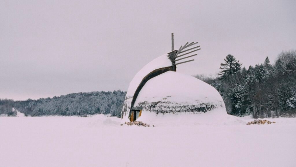 Snow covered AKI building. Architectural landmark in winter landscape. Snowy forest backdrop. Unique building design.
