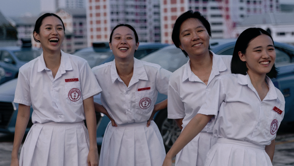 Four smiling Asian schoolgirls in white uniforms. Singaporean school scene.