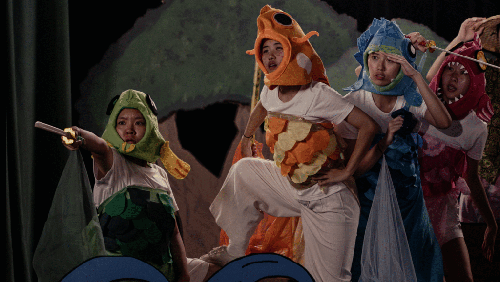 Theater performance with actors in colorful fish costumes. Stage production, creative costumes, and theatrical arts.