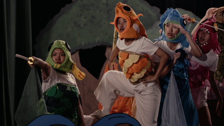 Theater performance with actors in colorful fish costumes. Stage production, creative costumes, and theatrical arts.