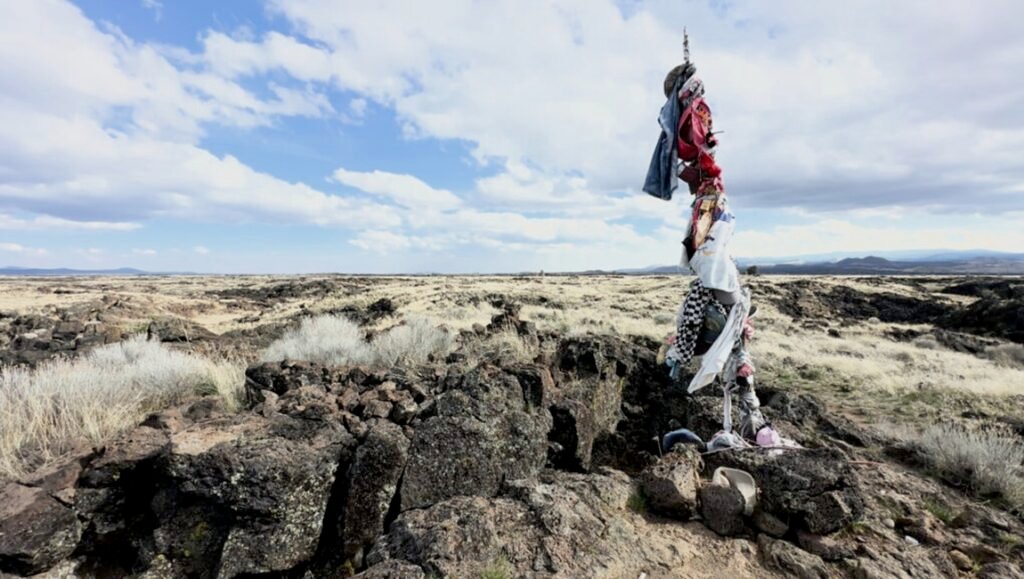Desert landscape with a pole adorned with clothing. Blue sky with clouds. Outdoor travel photography.