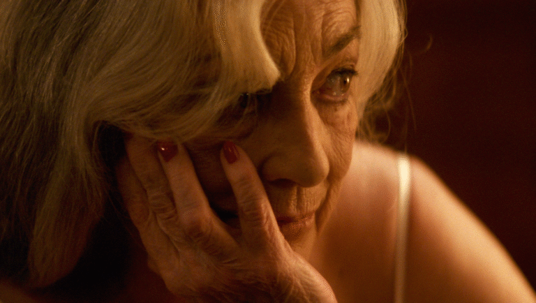 Still from Calle Málaga: Close-up of an older woman's face, hand resting on her cheek. TIFF '25 review.