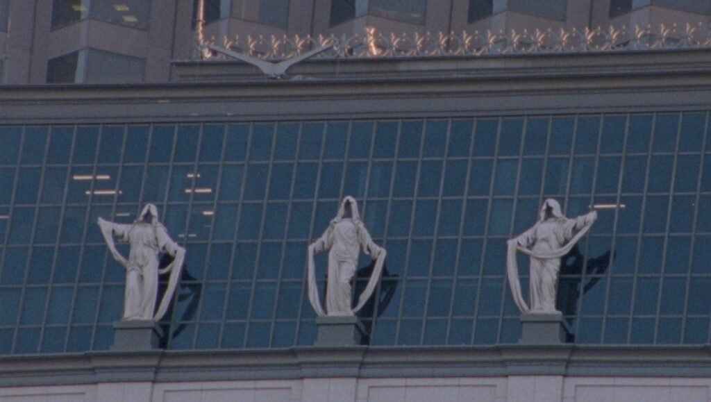 Three hooded statues adorn a building in Sinking Feeling by Epcar & Zachary, 2024. Art installation.