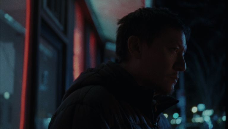Man in jacket at night. Moody lighting, urban scene. Portrait.