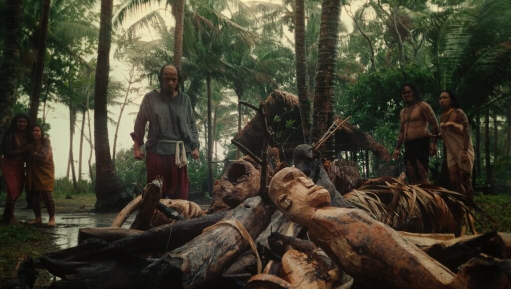 TIFF 2025 — Dispatch 1: A Private Life, Wrong Husband, Sirat Still from Magellan, TIFF 2025 film. Indigenous people stand near wooden carvings in a tropical setting.