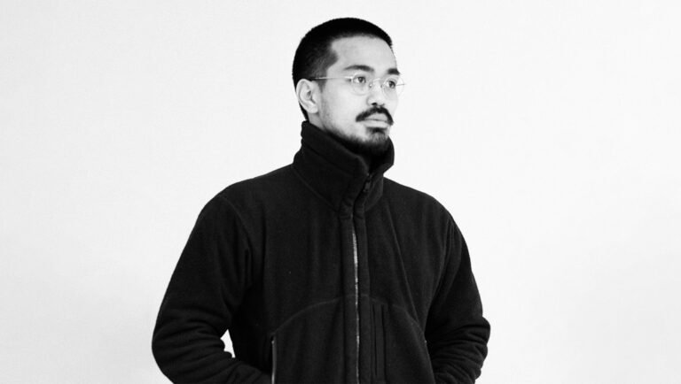Black and white portrait of Neo Sora, director, wearing glasses and a jacket. Photo by Aiko Masubuchi.