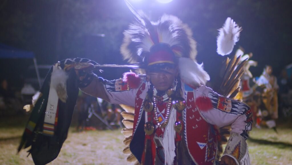 Native American dancer at a powwow. Indigenous culture, traditional clothing, and vibrant feather headdress.