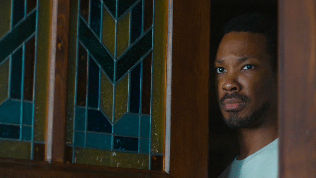 The Man in My Basement movie still. African-American man looking out from a doorway. Stained glass window.