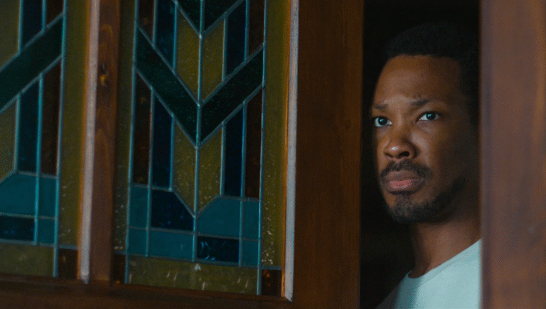 The Man in My Basement movie still. African-American man looking out from a doorway. Stained glass window.