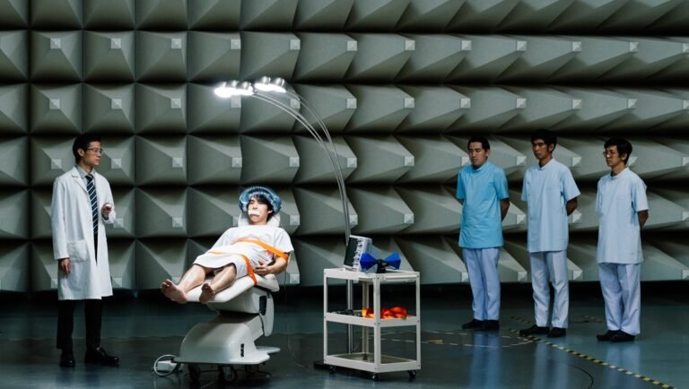 Still from Useful Ghost at TIFF 2025. Man in chair, doctors, soundproof room.