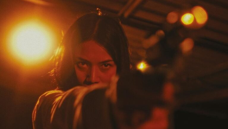 Laguna film still: Woman aiming gun. Intense, cinematic shot. Venice '25 review.