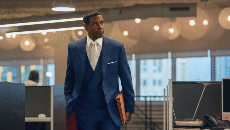 Denzel Washington in blue suit walks through open office with documents.