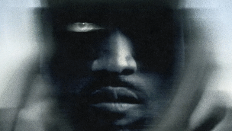 Film review: Him by Justin Tipping. Close-up of a man's face in dark tones, with one eye visible.