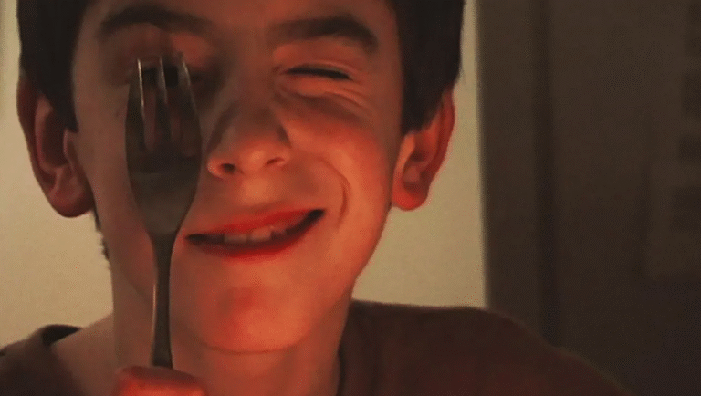 Boy with fork near eye. Funny face, squinting. Food safety, kitchen utensil.