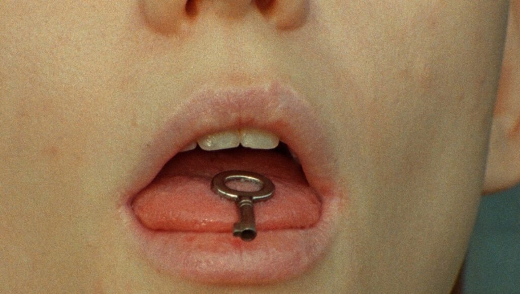 Open mouth with a key on the tongue. Conceptual art by Antoinette Zwirchmayr.