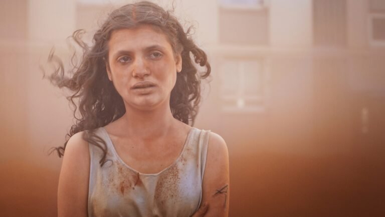 Alpha film still from London Film Festival. Woman with bloodstains and curly hair.
