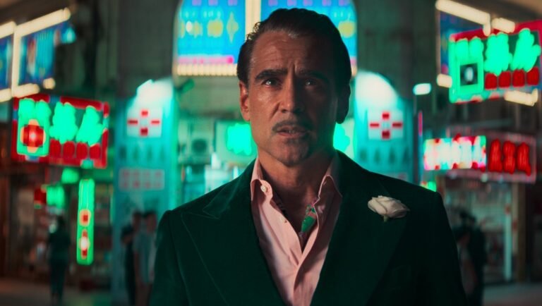 Colin Farrell in Sugar. Farrell wears a green suit with a white flower. Neon signs in the background.