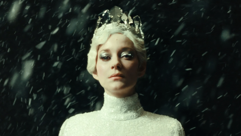 Ice Queen with crown in falling snow. Fantasy character with silver eye makeup and white dress.