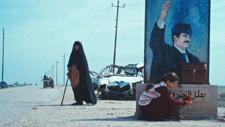 The President's Cake film still: Woman in niqab, girl with Saddam Hussein mural, wrecked car. LFF '25 review.