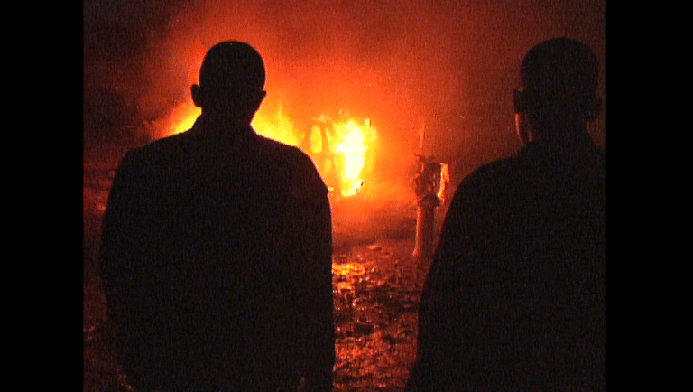 Still from Barrio Triste NYFF. Silhouetted figures watch a fire. Film review.