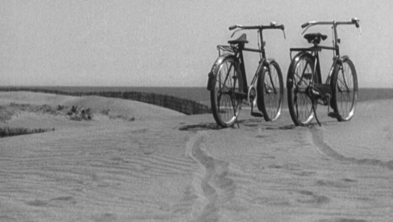 Late Spring film still: Two bicycles parked on a sandy beach near the ocean, evoking themes of time and transitions.