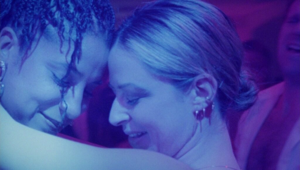 Follies film still: Two women embrace in blue light, showcasing the Tallinn Black Nights Film Festival's 'Tales of the Wounded Land'.