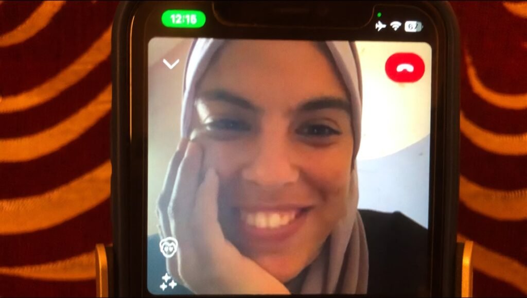 Sepideh Farsi on a phone screen. Smiling woman with hijab in a video call. Put Your Soul On Your Hand and Walk.