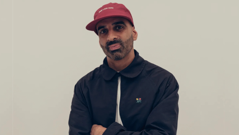 Reza Dahya headshot. Man in Aimé Leon Dore hat and black jacket. Fashion portrait.
