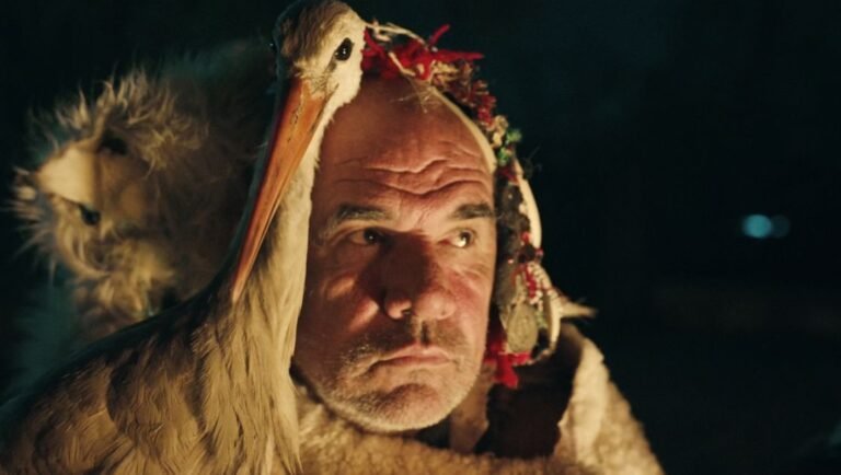 The Tale of Silyan review image: Nikola, adorned with a stork, in Tamara Kotevska's film, showcasing Macedonian culture.