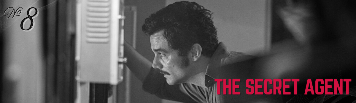 The Secret Agent movie still, featuring a man with a mustache, looking intently at a machine in a black and white scene.