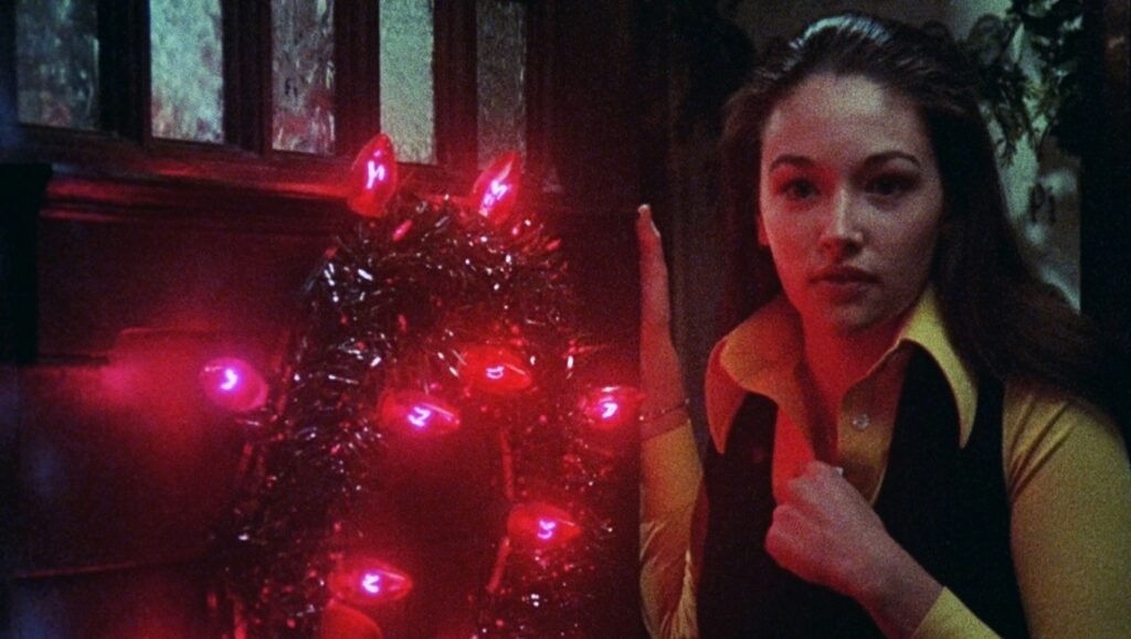 Black Christmas (1974) movie scene: Jess, a sorority sister, stands near a Christmas tree with ominous red lights.