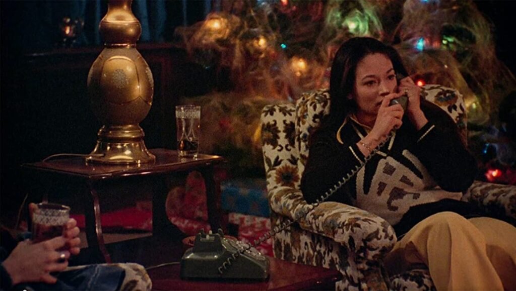 Black Christmas: Haunted by Absence Black Christmas 1974 scene: Woman on phone in vintage chair with Christmas tree. Classic horror film.