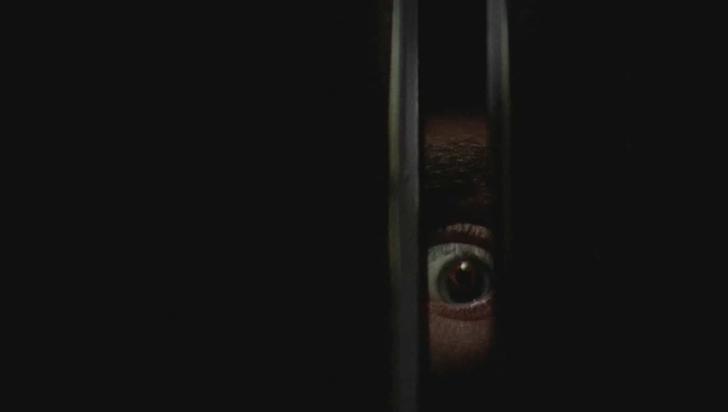 Black Christmas: A sinister eye peers through a crack, evoking suspense and horror in the haunted film.