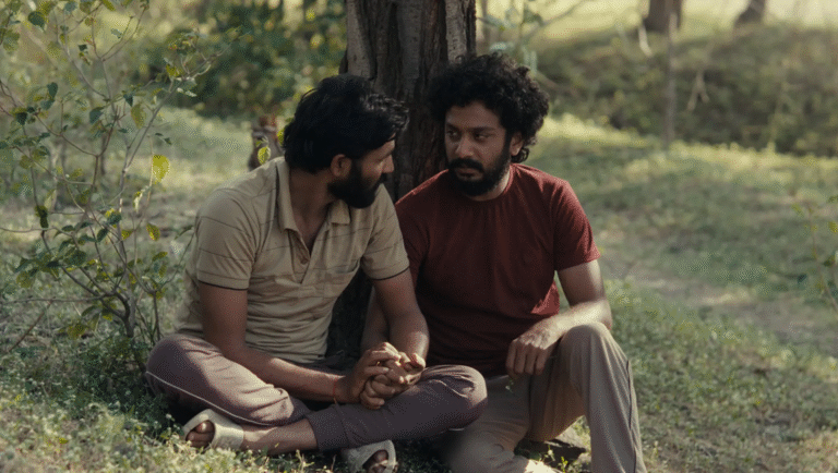Cactus Pears review: Two men hold hands sitting by a tree in a still from the film by Rohan Kanawade.