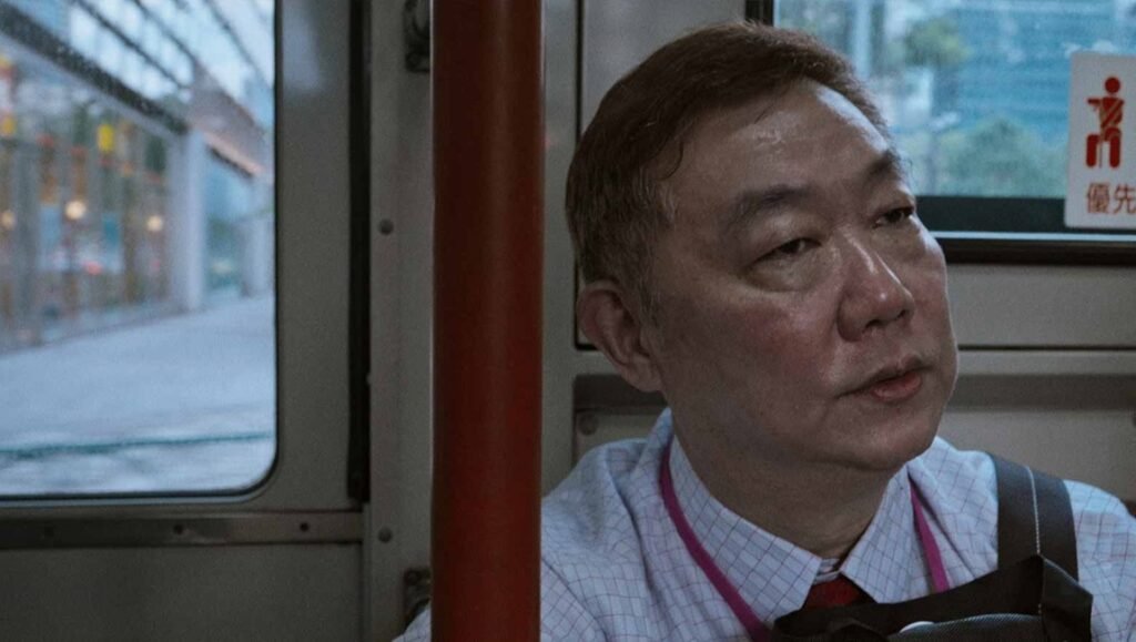 Film still from "The Old Man and His Car" at the Singapore International Film Festival, featuring an Asian man on a bus.