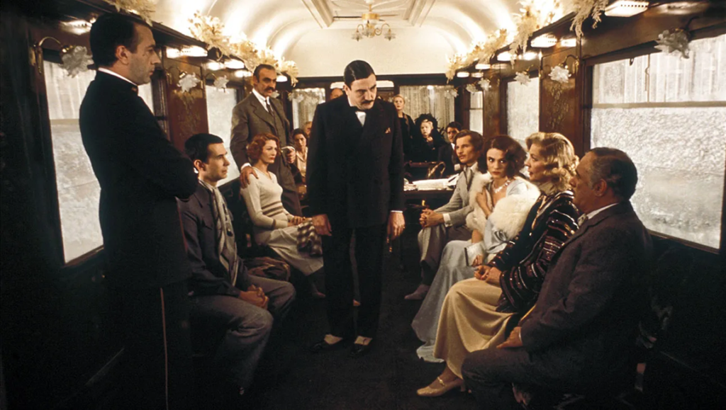 Murder on the Orient Express still. Group of people in a train car, a classic whodunit scene.