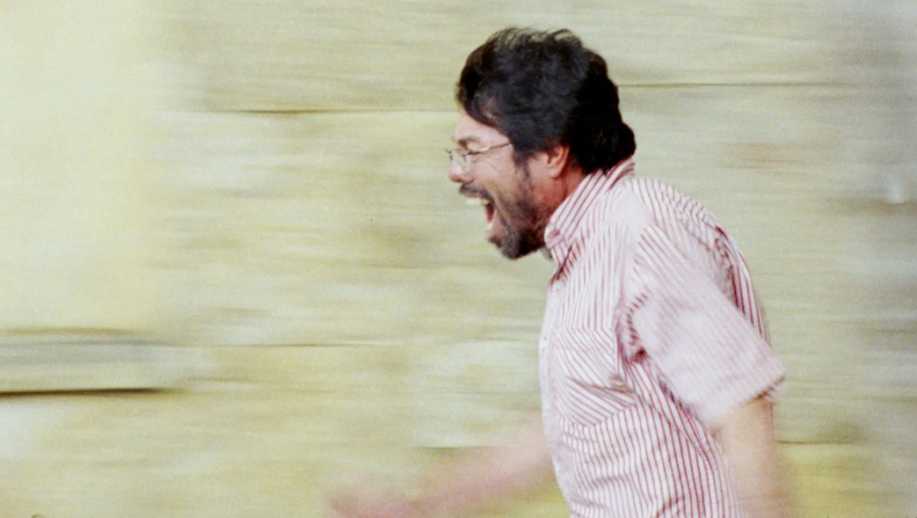 Simón Mesa Soto's 'A Poet' review image: Man in striped shirt shouting with blurred background, conveying intense emotion. Film review.