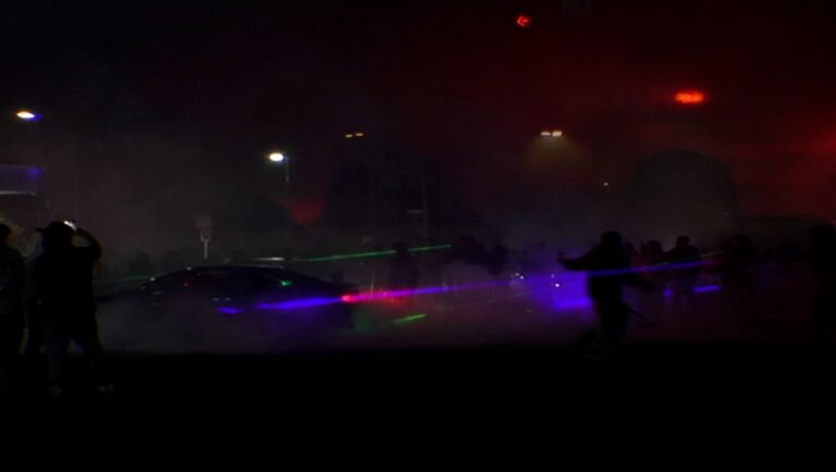 Still from 'Tycoon' film: A dark scene with a car, people, and colorful laser lights at the IFFR '26 review.