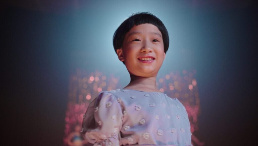 IFFR 2026 film still: A smiling young Asian girl in a dress, possibly from "Krakatoa, Honey Bunny, The Killing of Meghnad".